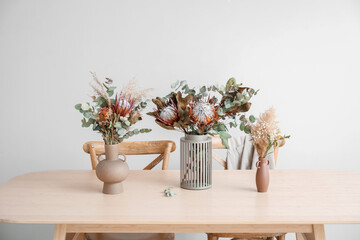 Vases with dried flowers on dining table in room