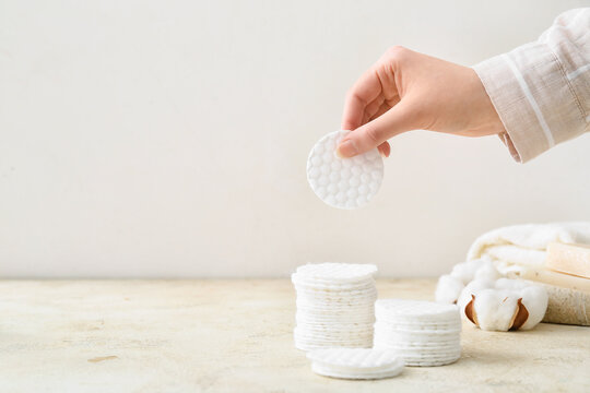 Female hand with new clean cotton pad on light background