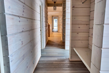 Interior of a corridor in a country house with natural wood walls and parquet