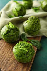 Wooden board with tasty spinach muffins on table