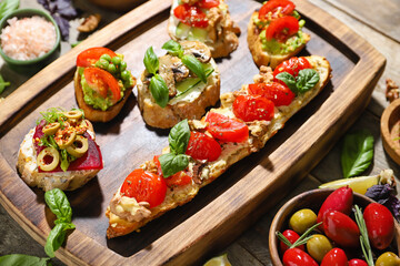 Board with delicious bruschettas with vegetables on table, closeup
