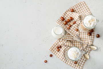 Glass cups of tasty latte and jug with milk on white background