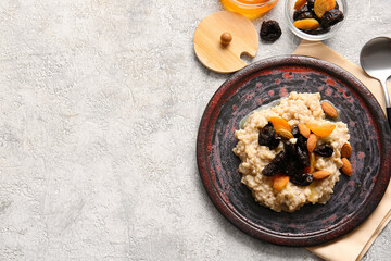 Tasty sweet oatmeal with prunes, dried apricots and almond nuts in plate, on light table