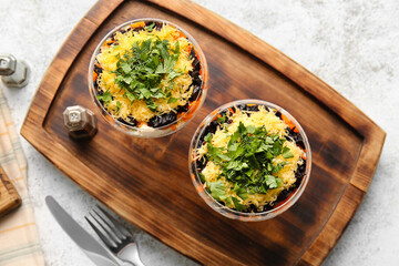 Delicious salad with prunes and greens in glasses on wooden board