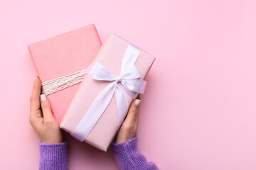 Woman holding gift boxes on pink background, closeup