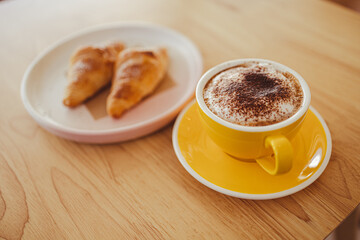 yellow coffee mugs on wooden table in cafe