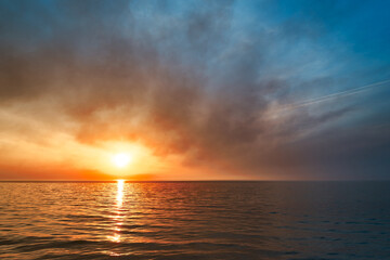 Obraz premium Sea sunset. Smoke wildfires sweeping across the sky.
