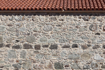 Part of an old stone wall and roof. Natural background or texture. High quality photo.