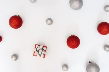 Christmas baubles decorations, red and silver colored balls and gift box New Year holiday pattern, flat lay.