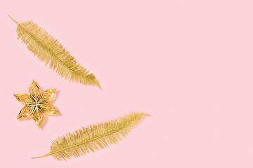 New Year background with metallic golden toys flower and palm leaves with empty space. Christmas decorations on pink colored paper. Creative Winter Holiday concept.