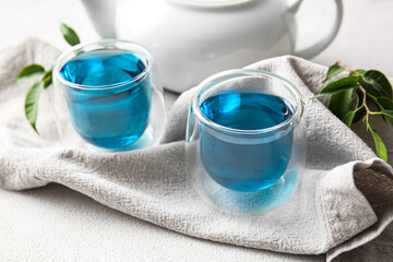 Glasses of organic blue tea on white background, closeup