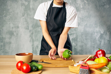 Cook woman on the kitchen cutting vegetables cutting board
