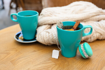 Blue cup of hot tea with cinnamon and macaron on table in cafe