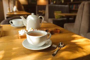 Cup of hot tea and spoon on table in cafe