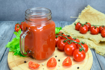 A jar of tomato juice, tomatoes and allspice on a cutting board and tomatoes on a coarse linen cloth lie side by side