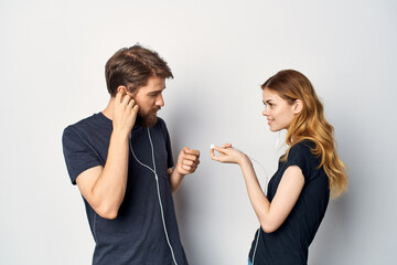 cheerful young couple with a phone in hand emotions in headphones light background