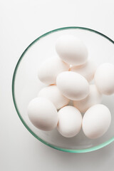 chicken eggs in a bowl and on a plate on a white background