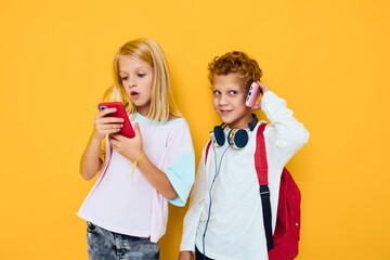 teenage boy and girl use gadgets with headphones yellow background