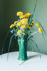 bouquet of yellow dandelions in clay vase