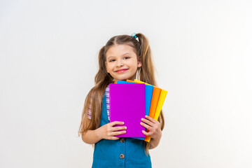 A schoolgirl with different textbooks in her hands on a white background.