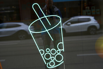 Light green neon bubble tea icon at shopping window at downtown Zürich on a cloudy day. Photo taken October 12th, 2021, Zurich, Switzerland.