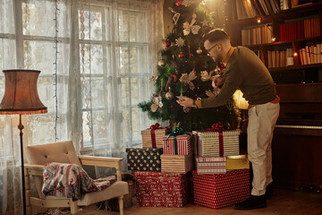 Man decorating Christmas tree at home