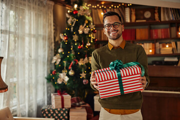 Obraz na płótnie Canvas Man holding Christmas gift in front fir