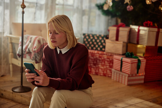 Woman looking at mobile phone in depression during Christmas time