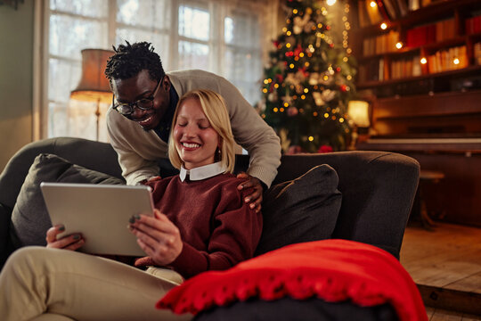 Smiling couple in love using table during Christmastime - Powered by Adobe
