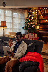 Happy black man in a Christmas mood using tablet.
