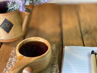 background made of oak planks and pine planks painted white on the table a bunch of lavender and a wooden cup with coffee and a notebook and a pen