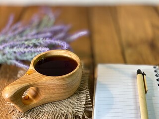background made of oak planks and pine planks painted white on the table a bunch of lavender and a wooden cup with coffee and a notebook and a pen