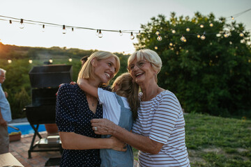 Portrait of grandmother with adult daughter and granddaughter relaxing in the backyard