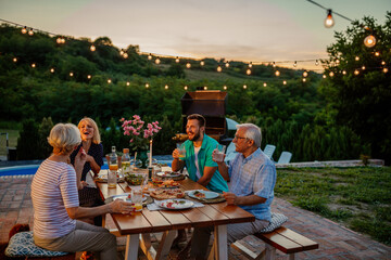 Three generations family family during dinner, celebrating holiday together in the backyard