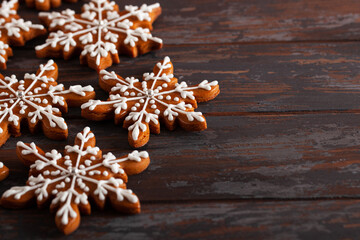 Christmas background with homemade snowflake shape gingerbread cookies on wooden background. New Year celebration traditions concept.