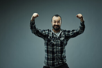 Bearded man in check shirt raising hands in triumph