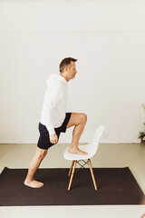 Middle-aged man doing step up stretch exercises using a chair