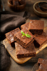 Chocolate brownie pie slices in a white plate on the dark background. Homemade blondie bars traditional American dessert closeup