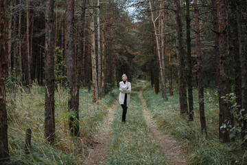 Fototapeta premium portrait of a girl in black with a light cape among the autumn forest