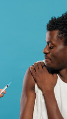 Hands of doctor preparing to vaccinate young man against coronavirus. Portrait of person being...