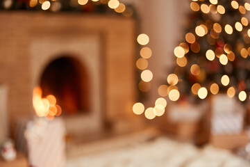Blurred image of living room with fireplace and Christmas tree decorated with garland lights and...