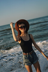 Fototapeta na wymiar cheerful woman in sunglasses and a hat by the ocean walk summer
