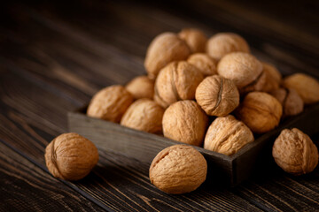 Still life of walnuts lying on a dark wooden table.