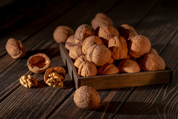 Still life of walnuts lying on a dark wooden table.