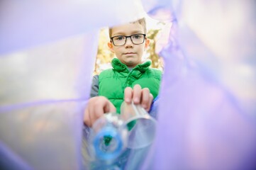 A seven-year-old boy at sunset is engaged in garbage collection in the park. Environmental care,...