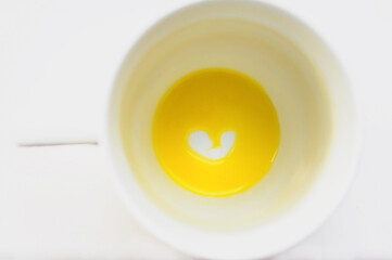 White cup with orange juice heart on a white background. Declaration of love. Valentine's day card