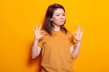 Optimistic person showing approval gesture on camera. Caucasian woman doing okay sign with fingers and smiling, feeling confident about achievement. Adult having positive expression