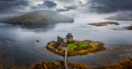 Panoramic aerial view of the impressive Eilean Donan Castle in the Highlands of Scotland with misty mountains and rain, United Kingdom