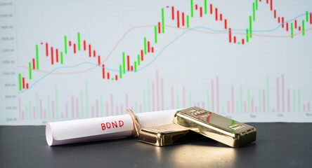Concept of gold bond showing with Gold bars and Bond paper with Stock Market Graphs or charts in...