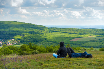 Fototapeta na wymiar Hikers relaxing sitting on the ground against green hills